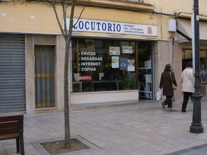 Fachada estrecha de un locutorio en una calle de ciudad